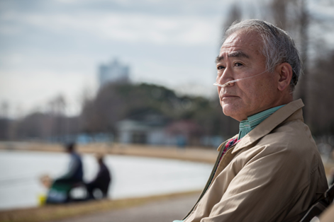 Picture of an elderly man with oxygen sitting on a bench